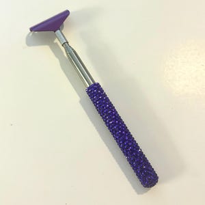 May include: A purple and silver back scratcher with a crystal-covered handle.