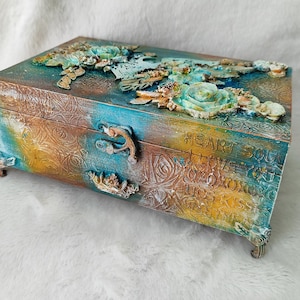 Caja de madera con pájaro y flores de arcilla. Caja de color turquesa y marrón.