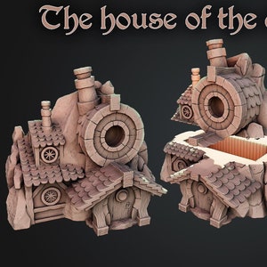 Peut inclure: Modèle imprimé en 3D d'une maison de mineur nain, en pierre et en bois, avec une grande ouverture ronde sur le côté. La maison est construite dans une colline rocheuse et possède une cheminée et une petite porte.