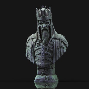Può includere: Un busto in scultura grigio e dettagliato di un re con una corona e una lunga barba. Il busto è su una base con teschi.
