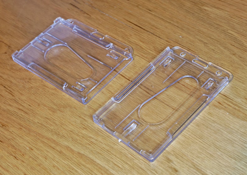 K&ouml;nnte beinhalten: Zwei transparente Plastik-Ausweishalter. Die Halter sind f&uuml;r die Aufnahme eines standardm&auml;&szlig;igen Personalausweises oder einer Kreditkarte konzipiert.