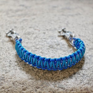 May include: A blue and white paracord leash with silver metal clasps. The leash is made with a braided pattern.