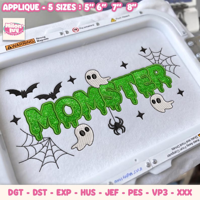 May include: An embroidery design in a white hoop featuring the green glittery text "MOMSTER" in a dripping font. The design includes three white ghosts, two black bats, two spider webs, a black spider, and several small black four-pointed stars.