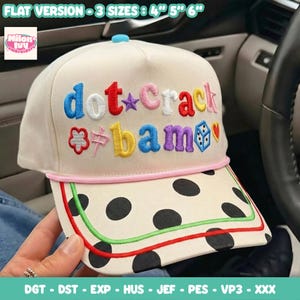 Peut inclure: Une casquette de baseball crème avec du texte brodé dot crack bam en lettres colorées, une étoile violette, une fleur, un dé et un cœur. La visière est crème à pois noirs avec un liseré rouge et vert, disponible en tailles 4, 5 et 6 pouces.