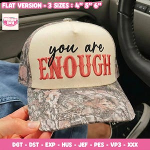 May include: A baseball cap with a cream-colored front panel featuring the embroidered black text you and the red text ENOUGH. The brim and side panels have a camouflage pattern. Text at the top indicates FLAT VERSION - 3 SIZES : 4" 5" 6".