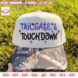 Op de afbeelding: Een beige honkbalpet met een klep in camouflageprint. Het voorpaneel is voorzien van paars geborduurde tekst TAILGATE & en zwart geborduurde tekst TOUCHDOWN, geaccentueerd met kleine paarse en zwarte vierpuntige sterren.