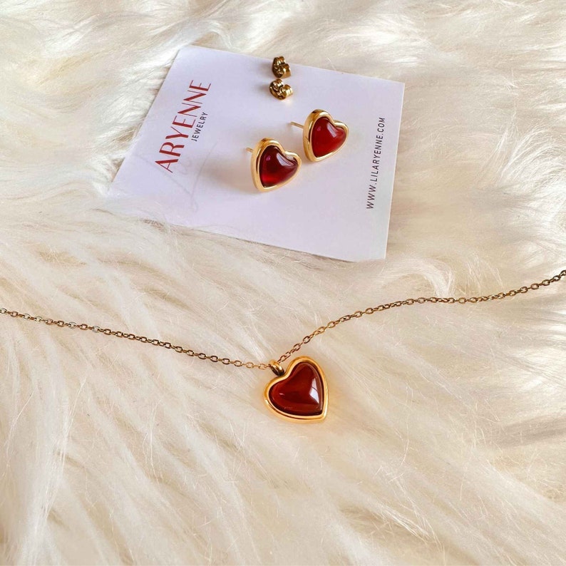 Gold heart shaped Carnelian crystal necklace and gold heart shaped carnelian crystal earrings located on a plaque with the LilAryenne logo.