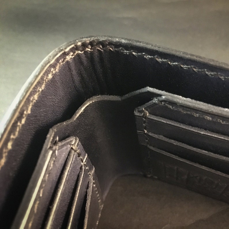 May include: Close-up of the interior of a black leather wallet, showing multiple card slots and a stitched edge.