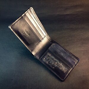 May include: A black leather wallet with a stitched design and the word "BLACKST" embossed on the front.