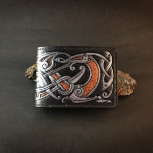 May include: Black leather wallet with a silver and orange embossed design of a dragon with intricate knotwork.