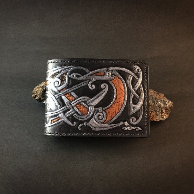 May include: Black leather wallet with a silver and orange embossed design of a dragon with intricate knotwork.