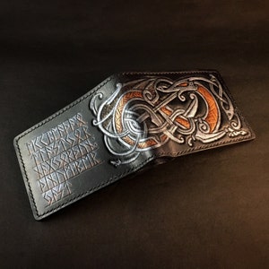 May include: Black leather wallet with a silver and orange dragon design and runes on the front.