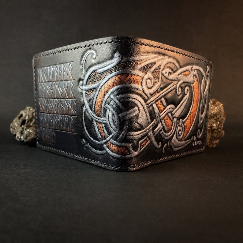 May include: Black leather wallet with a silver and copper embossed design of a dragon and runes.
