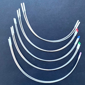 May include: A set of seven silver-coloured wire hoops with white plastic tips. The hoops are arranged in a semi-circle, with the largest hoop at the top and the smallest hoop at the bottom. The hoops are all the same shape and size, but they have different coloured tips.