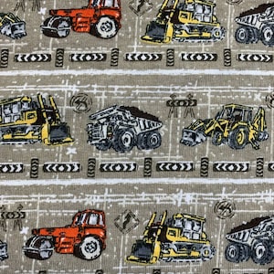 May include: A beige fabric with a repeating pattern of construction vehicles. The vehicles are yellow, orange, and gray. The pattern includes construction signs and tire tracks.