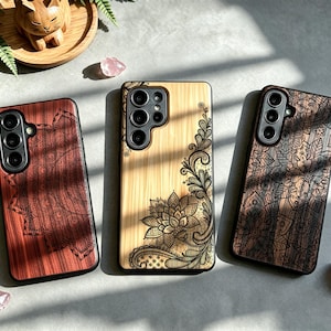 May include: Three rectangular smartphone cases featuring wood-grain textures and intricate laser-engraved floral and lace patterns. The left case is reddish-brown, the center case is light tan, and the right case is dark brown, each with black camera cutouts.