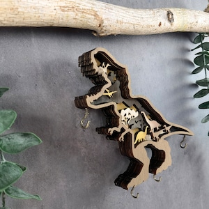 May include: A wooden dinosaur wall hook with a layered design featuring multiple dinosaurs. The hook is brown with gold accents and has four hooks for hanging items.