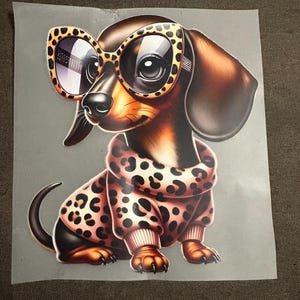 Könnte beinhalten: Eine digitale Illustration eines Dackels mit übergroßen Sonnenbrillen im Leopardenmuster und einem passenden Pullover. Der Hund ist braun, schwarz und hellbraun, mit einem verspielten Ausdruck. Der Hintergrund ist einfarbig grau.