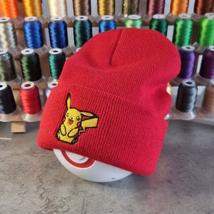Puede incluir: Gorro de punto rojo con un personaje Pikachu bordado en amarillo.