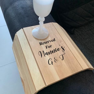 May include: Wooden tray with a black inscription that reads "Reserved for Nannie's G&T". A white glass sits on the tray.