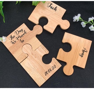 Puede incluir: Dos piezas de rompecabezas de madera con el texto "The Day We Moved In" y "20.06.22" en una pieza y "Jack" y "Jenny" en las otras piezas.