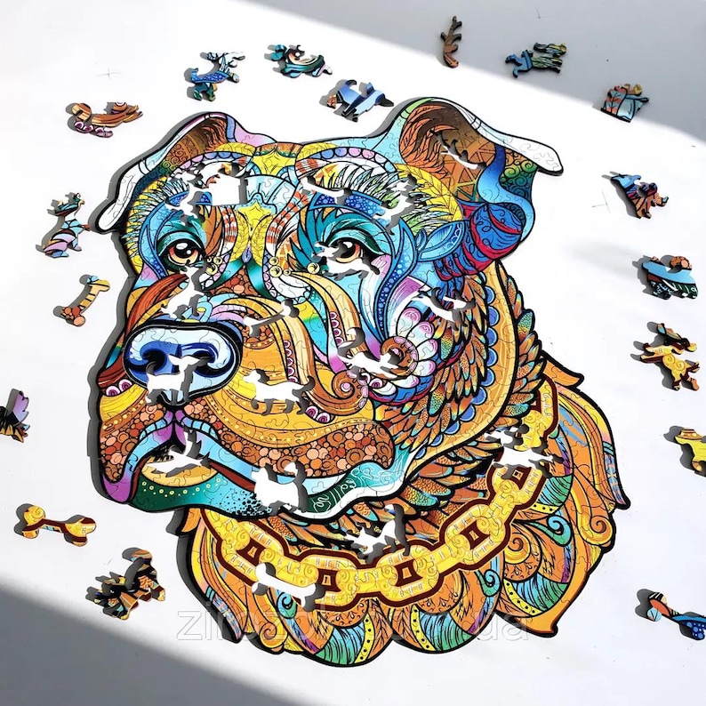 Puede incluir: Un colorido rompecabezas de madera con la imagen de la cabeza de un perro con intrincados patrones en tonos azules, amarillos, naranjas y marrones. Varias piezas peque&ntilde;as y &uacute;nicas del rompecabezas est&aacute;n dispersas.