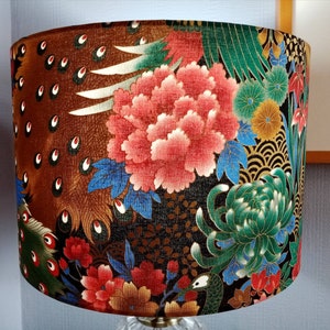 May include: A lampshade with a dark brown background and a colorful floral pattern. The pattern includes red, pink, green, and gold flowers, as well as peacock feathers.