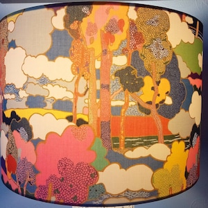 Pode incluir: Um abajur com um design abstrato colorido que apresenta &aacute;rvores, nuvens e uma paisagem. O design &eacute; em tons de azul, verde, amarelo, rosa e laranja.