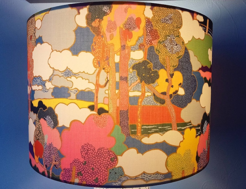 Pode incluir: Um abajur com um design abstrato colorido que apresenta &aacute;rvores, nuvens e uma paisagem. O design &eacute; em tons de azul, verde, amarelo, rosa e laranja.