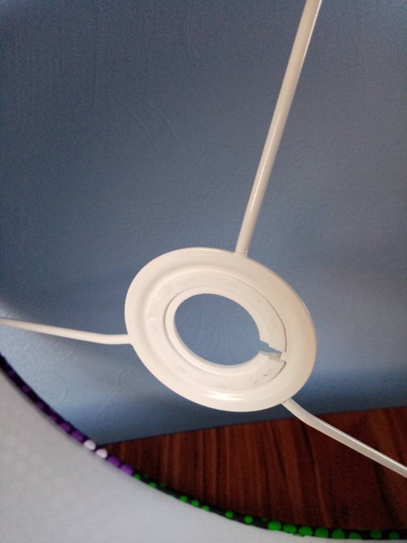 May include: White lampshade fitting with a blue fabric lampshade. The lampshade has a purple and green trim.