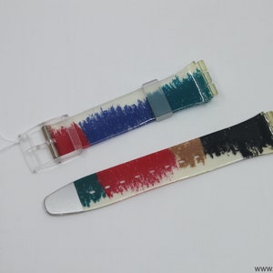 May include: Two colorful watch bands with a white background and a brushstroke pattern. The bands are made of clear plastic with a silver buckle. The text "Gk 249 1999 blgr slider" is written on a white tag.
