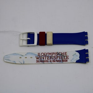 May include: A white and blue watch strap with a red and white stripe. The strap has the text "II. OLYMPISCHE WINTERSPIELE St. Moritz 11.-19. Febr. 1928" printed on it.