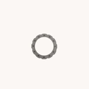 May include: A gray, circular watch bezel with a series of numbers from 00 to 55, indicating minutes. The bezel is made of a matte material and has a simple, modern design. The numbers are evenly spaced around the outer edge.