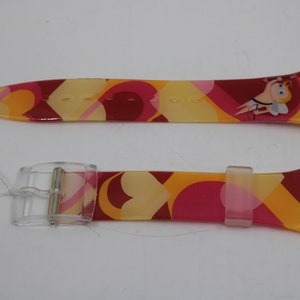 May include: A pink, yellow, and orange watch band with a clear plastic buckle. The band has a heart pattern and a cartoon cupid design.