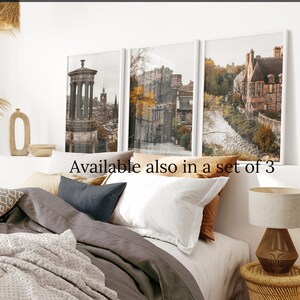 May include: Three framed prints of Edinburgh, Scotland. The prints feature a cityscape with buildings, a castle, and a street scene. The prints are in a modern style with a muted colour palette.