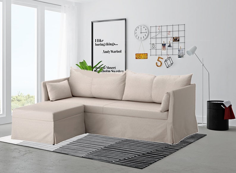 May include: A beige sectional sofa with a chaise lounge and two pillows. The sofa is in a living room with a black and white striped rug, a black trash can, and a floor lamp.