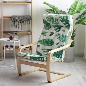 May include: A wooden armchair with a white and green tropical leaf patterned cushion. The chair has a curved back and a wide seat.