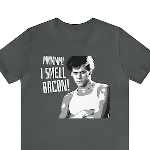 May include: A dark gray t-shirt with a white graphic of a man with the text "MMMMM! I SMELL BACON!"