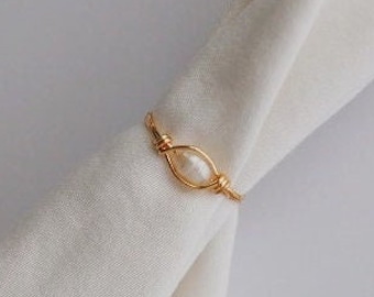 May include: A gold wire ring with a white pearl accent.