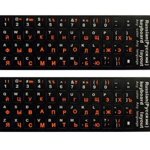Puede incluir: Pegatinas de teclado negras con letras y símbolos cirílicos naranjas para una disposición de teclado rusa. Las pegatinas están etiquetadas "Russian (Русский) layout".