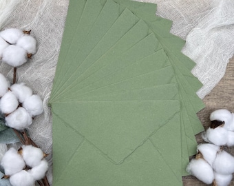 May include: A stack of 10 sage green envelopes with a flap on the top. The envelopes are made of textured paper and have a rustic look.