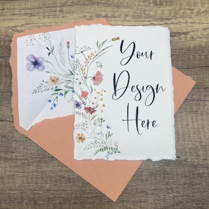 May include: A blank card with a floral design on the left side and the text "Your Design Here" on the right side. The card is sitting on a peach-colored envelope.