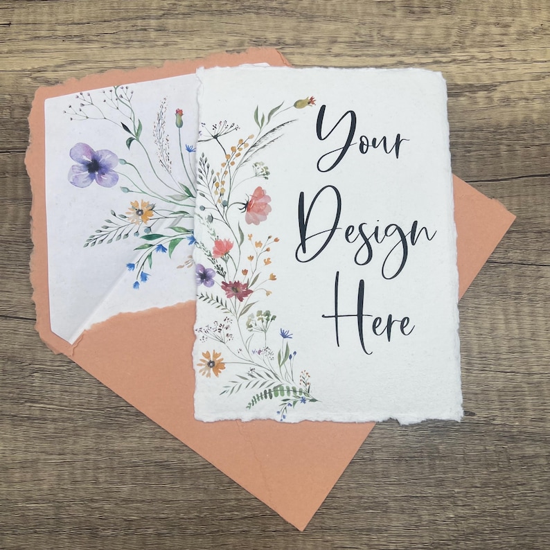 May include: A blank card with a floral design on the left side and the text "Your Design Here" on the right side. The card is sitting on a peach-colored envelope.