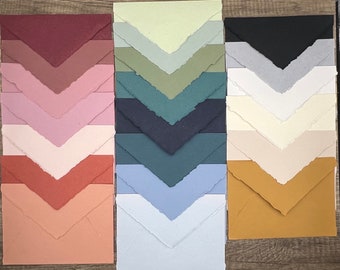 May include: A collection of 10 different colored envelopes with a textured, handmade paper finish. The envelopes are arranged in two rows of five, with each row featuring a different color palette.