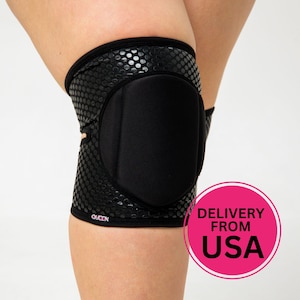May include: Black knee pad with a textured, dotted pattern. The pad has a thick, black cushion for protection and the word "QUEEN" is printed on the side. The knee pad is designed to protect the knee.