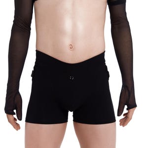 Può includere: Pantaloncini neri dal design unico, con un dettaglio a bottone. I pantaloncini sono abbinati a un top nero trasparente con maniche lunghe che coprono le braccia e le mani. L'outfit è progettato per un'estetica moderna.