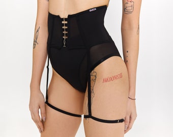 Op de afbeelding: Zwarte lingerie set met een hoge taille corset met goudkleurige sluitingen en een jarretelgordel. Het woord "QUEEN" is op de tailleband gedrukt. De set is gemaakt van ondoorzichtige en transparante stoffen.