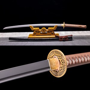 Könnte beinhalten: Ein traditionelles japanisches Katana-Schwert mit einer schwarzen Scheide und einem braunen Ledergriff. Das Schwert wird auf einem Holzständer mit aufwendigen Schnitzereien präsentiert.