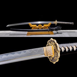 May include: A traditional Japanese katana sword with a black scabbard and a gold-colored hilt. The sword is displayed on a wooden stand with intricate carvings.