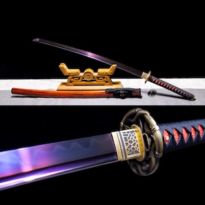 May include: A purple and black katana sword with a gold and black handle. The sword is on a wooden stand with a red and brown scabbard.
